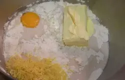 К смеси из дрожжей, муки и молока добавить яичный желток, тертую цедру лимона и 1/3 оставшегося масла