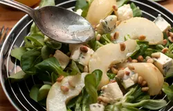 На листья салата выложите груши, нарезанный кубиками сыр, посыпьте орешками и полейте заправкой.