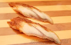 Достаньте угря для суши (unagi kabayaki) из упаковки, разморозьте, снимите шкуру и разрежьте рыбу вдоль на две половины. Держа нож наискосок относительно рыбы и почти параллельно доске, нарежьте угря длинными ломтиками. Половину листа нори разрежьте на тонкие полоски, они пригодятся для того, чтобы закреплять рыбу на рисе.