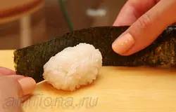 Возьмите "ленточку" из нори и оберните ей рис. 