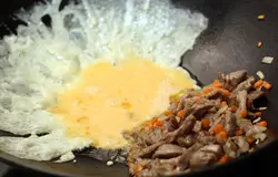 Теперь сдвиньте мясо на край вока, а в середину вылейте взбитое яйцо.