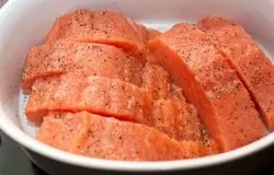 Филе лосося нарежьте продолговатыми кусочками шириной 4-5 см, положите в неглубокую форму для запекания. Старайтесь укладывать рыбу плотно, не оставляйте большие зазоры между кусками, иначе соуса потребуется слишком много.  Посолите, поперчите и сбрызните лимонным соком.