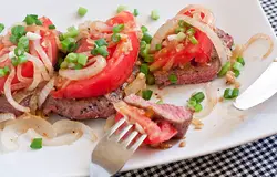Выложите овощи поверх мяса, посыпьте нарезанной зеленью и подавайте, пока блюдо горячее.
