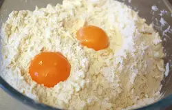Добавляем 2 яичных желтка и быстро замешиваем тесто. Можно добавить в тесто пару столовых ложек коньяка или рома — это придаст аромат и сделает тесто более пластичным.