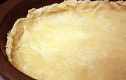 Охлажденное тесто раскатываем и распределяем руками по широкой плоской форме для выпечки, накалываем вилкой, насыпаем сухой фасоли и ставим в разогретую до 190 градусов духовку минут на 15.