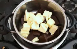 Шоколад поломать на кусочки, положить в емкость.  Туда же добавить кубики масла. Сделать водяную баню - поставить емкость с шоколадом в кастрюлю с водой (вода не должна касаться низа кастрюли).