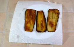 Снять баклажаны и  выложить их на салфетку, чтобы впиталось лишнее масло. Так же пожарить все остальные пластинки баклажанов.