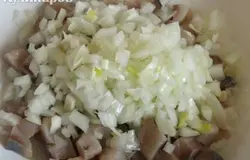 В салатник положить нарезанные кубиками сельдь, лук.