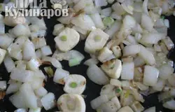 Отложить мясо в сторону. На сковороде, где жарилось мясо, обжарить мелко нарезанный лук в течение 5-7 мин. Затем добавить чеснок, нарезанный пластинками или мелко.