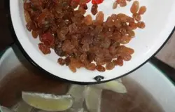 Сложить кусочки лимона в кастрюлю, залить горячей кипяченой водой. После этого добавить сахар. Затем засыпать немного изюма, хорошо все перемешать до полного растворения сахара.