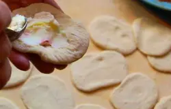 Теперь возьмемся за тесто. Для этой выпечки можно использовать, как покупное дрожжевое тесто, так и самостоятельно приготовленное в домашних условиях. Разделите тесто на одинаковые кусочки в форме шариков, размеров около 5 см и оставьте их примерно на 5 минут, чтоб они поднялись. Из каждого шарика сделайте лепешки и в центр выкладывайте начинку. Соединяем края и придаем форму пирожка.