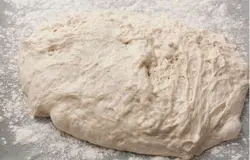 В теплой кипяченой воде растворить и смешать соль, сахар и сухие дрожжи. Чтобы дрожжи растворились и набухли – поставить емкость в темное теплое место. Смешать просеянную муку с содой, добавить щепоточку сушеного укропа. После полного растворения дрожжей, добавить их к муке. Раздавить зубик чеснока и добавить в тесто. Замесить нетугое тесто, которое немного будет прилипать к пальцам.
