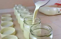 Затем залейте закваску (натуральный йогурт) молоком, которое уже остыло. Его нужно взять приблизительно ½ 200 граммового стакана. Помешайте ложечкой. Потом долейте остальное количество молока. Снова перемешайте.