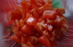 Долее займитесь помидорами. Томаты помойте. Затем нарежьте кусочками произвольной величины. Если вы не хотите, чтобы в блюде ощущались шкурки, тогда опустите помидоры в кипяток. Через 60 секунд окуните томаты в миску с водой. Затем аккуратно снимите кожицу, а только после этого нарезайте.