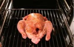 Разогрейте духовку. Положите курицу на решетку. Температура запекания должна быть от 180°С до 200°С. Жарьте курицу где-то полтора-два часа. А, чтобы жир не горел, налейте в противень немного воды и поставьте его вниз, под курицу. Проткните ее ножом, если сок светлый – курица готова, а если с кровью, тогда нет.