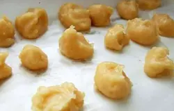 Профитроли с шоколадным кремом В сотейнике растапливаем масло, добавляем воду, и доводим до кипения. Затем всыпаем муку. Снимаем смесь с огня и очень хорошо взбиваем. Охлаждаем до 30 °С. Яйцо взбиваем и постепенно добавляем в тесто. Разогреваем духовку до 220 °С градусов. Смазываем противень водой. Тесто перекладываем в кулинарный мешок и в виде маленьких шариков выпускаем его на противень. Выпекаем 10 минут, затем температуру снижаем до 190 °С и печем еще около 25 минут.