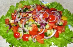 Порезать крупными кубиками помидоры, болгарский перец и огурец, посолить, выложить эту смесь на листья салата. Красный лук порезать тонкими полукольцами и посыпать сверху.