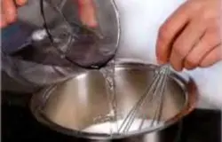 Изюм помыть, залить теплой кипяченой водой. Орехи обжарить на раскаленной сухой сковороде, растолочь в крупную крошку. Цукаты порезать небольшими кусочками. Миксером взбить сливки на большой скорости до устойчивой, но мягкой пены, 3 мин., поместить в холодильник. Сахар засыпать в сотейник, влить 40 мл воды и, постоянно помешивая, довести до кипения, 5 мин.