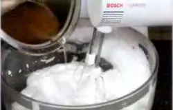 Белки взбить миксером. Продолжая взбивать, на самой медленной скорости, тонкой струйкой влить горячий сахарный сироп. Увеличить скорость и взбивать до тех пор, пока белки не будут устойчиво держаться на венчике.