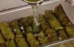 Разместить рулеты в кастрюлю в один ряд, залить ранее оставленным отваром так, чтобы он только покрывал их. Переместить на огонь, закипятить. Убавить огонь, закрыть крышкой и тушить 30 минут. Сделать заправку, смешав масло с лимонным соком.