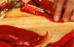 Достать перцы из духовки, остудить до комнатной температуры. Разрезать каждый перец вдоль на две части. Очистить от семян и плодоножек. (Хариссу можно приготовить двумя методами - блендером или руками. Если вы используете блендер, то кроме семян и плодоножек надо снять и кожицу. А если будете нарезать ножом, кожицу можно оставить. При работе вручную, стоит использовать перчатки (кулинарные).)
