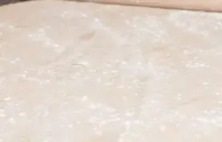 Посыпать немного муки на рабочую поверхность и раскатать тесто в тонкий широкий блин.