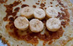 Готовятся эти блины очень быстро, но вкус вас просто удивит. Выпекаем блины по своему любимому рецепту. Для этого блюда нам понадобится 4 блина. Бананы очищаем от кожуры и нарезаем нетолстыми кружочками. Выкладываем бананы по диаметру блина.
