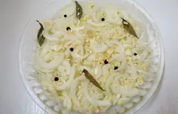 Дно огнеупорной формы смазываем растительным маслом. На масло выкладываем лук. На лук выкладываем лавровые листья и душистый перец и половину чеснока, слегка солим.