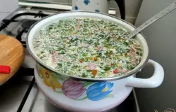 Начинаем сборку супа. К картофельному пюре доливаем частями бульон от копчёных рёбер и тщательно перемешиваем, пока полностью не разбавится пюре. Долейте весь бульон. Затем добавим нарезанные охотничьи сосиски, порезанный копчёный куриный окорочек, пассерованные лук, морковь и муку. В конце добавим сливки и мелко порезанную зелень и лавровый лист.
