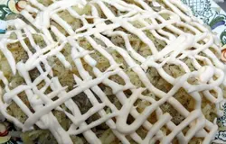 На грибы натираем на крупной тёрке отварной картофель. Солим его и перчим. Сверху покрываем сеточкой из майонеза