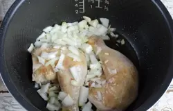Когда кусочки курочки слегка подрумянятся, добавьте в чашу порезанную луковицу и чеснок. Помешайте лопаткой и продолжайте жарить еще 10 минут.