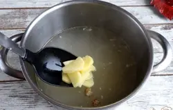 Возьмем картофель, очистим его и порежем. Закладываем картофель в бульон и поставим вариться.