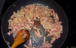 Тем временем лук и бекон мелко порезать и высыпать в другую сковороду, жарить минут 10 на среднем огне.