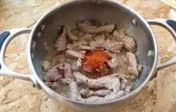К обжаренному мясу добавляем специи.Вливаем 1 стакан бульона. Накрываем сотейник крышкой и тушим на маленьком огне 1 час.