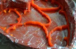 Форму выложить пищевой пленкой и разложить полоски перца так, чтобы образовались  "прожилочки"
