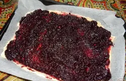 Большую часть теста раскатываю (не тонко, около сантиметра толщиной) и кладу на противень, смазанный растительным маслом или застеленный бумагой для выпечки. Распределяю по тесту начинку - черносмородиновый джем.