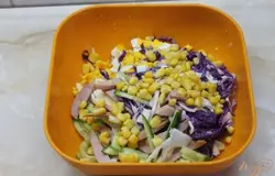 Соединяем в глубокой миске капусту, огурцы, сосиски, яйцо куриное и кукурузу консервированную.