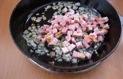 У меня бекон с крупными прослойками мяса. Такой бекон в продаже еще называется грудинкой. Его следует нарезать мелко. Добавляем его к луку.