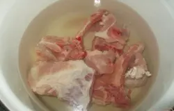 Свиные ребра положить в кастрюлю и, залив водой, поставить на огонь.