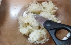 Кислую капусту отжимаем, кладем в миску и режем ножницами.