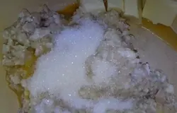 Сварить кашу из овсяных хлопьев, требующих варки (5-7 минут) и молока. Остудить её и добавить яйцо, сахар и кусочки растительно-сливочной смеси.