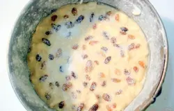 Форму смажьте маслом и посыпьте мукой. Тесто выложите в форму. Сверху посыпьте изюмом, а затем второй половиной сахара.