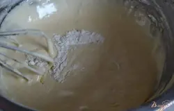 Постепенно небольшими порциями добавить просеянную муку, хорошо перемешивая .