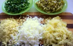 Отварить картофель в мундире и яйца. Почистить от кожицы и скорлупы. Картофель натереть на терке, яйца разделить на белки и желтки и тоже натереть. Зеленый лук и огурец мелко нарезать.