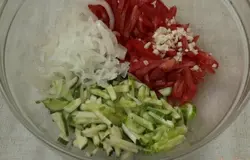 Соломкой нарезать огурцы и помидоры. Лук нарезать полукольцами, залить кипятком и обдать холодной водой, так уйдёт лишняя горечь. Если лук не очень горький, то можно этого не делать. Добавить лук к овощам, нарезать мелко чеснок.