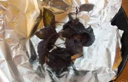 Сковородку застелите фольгой и положите на дно половину веточек базилика. Влейте половину растительного масла.