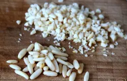 Нарезать кусочками поджаренные на сухой сковороде орешки пинии (кедровые)