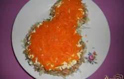 От вареной моркови отрезаем две стибочки для украшения салата, остальную натираем на крупной терке и выкладываем на желтки.