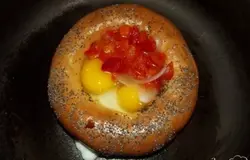 Морковь очистите от кожуры и хорошенько вымойте. Нарежьте ее не крупными кубиками и вложив в глубокую мисочку, залейте столовой ложкой оливкового масла и перемешайте. Лук нарежьте крупными кольцами и не разнимая их, вложите в миску. Залейте лук водой так, чтобы она полностью его покрыла. Воду посолите, поперчите красным перцем и добавьте столовую ложку яблочного уксуса. Оправьте лук на нижнюю полку холодильника. Красный болгарский перец очистите от семян и вымойте. Также можно использовать желтый, но не зеленый перец. Нарежьте его мелкими кубиками, примерно размером как и морковку. Когда бублик будет готов, достаньте его и промокните с обеих сторон. Смешайте лук, морковь и перец вместе. Переложите овощи в ковшик и залив водой проварите минуты четыре-пять. Сковородку разогрейте. Положите бублик и хорошенько прижмите по всей площади его к сковородке, чтобы между ними не оставалось зазоров. Вбейте во внутрь бублика два яйца (больше обычно не помещается) и высыпьте овощи, предварительно немного их обсушив. Сразу сверху посыпьте мелко порванным свежим укропом или любой другой зеленью по вкусу. Накройте крышкой и через пять минут добавьте пол кружки воды. Готовьте до готовности яйца.