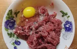 По прошествии 15 минут добавляем одно куриное яйцо и солим по вкусу. Пробуйте фарш на соль и чтобы фрикадельки были вкусными он должен быть слегка пересолен. Дальше перемешиваем фарш с яйцом. Теперь очень важный момент - фарш необходимо сильно отбить. Для этого берите его весь сразу руками и кидайте в миску. Так нужно делать до тех пор, пока он не перестанет разваливаться на части. Благодаря этой процедуре фарш будет легко скатываться в шарик, а фрикадельки держать форму.